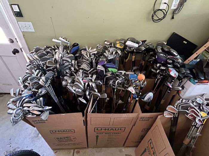 Boxes filled with inherited golf clubs arranged neatly in a garage setting.