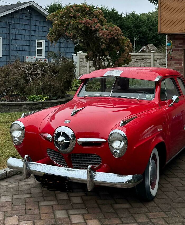 A vintage red car parked in a driveway, showcasing a cool inheritance.