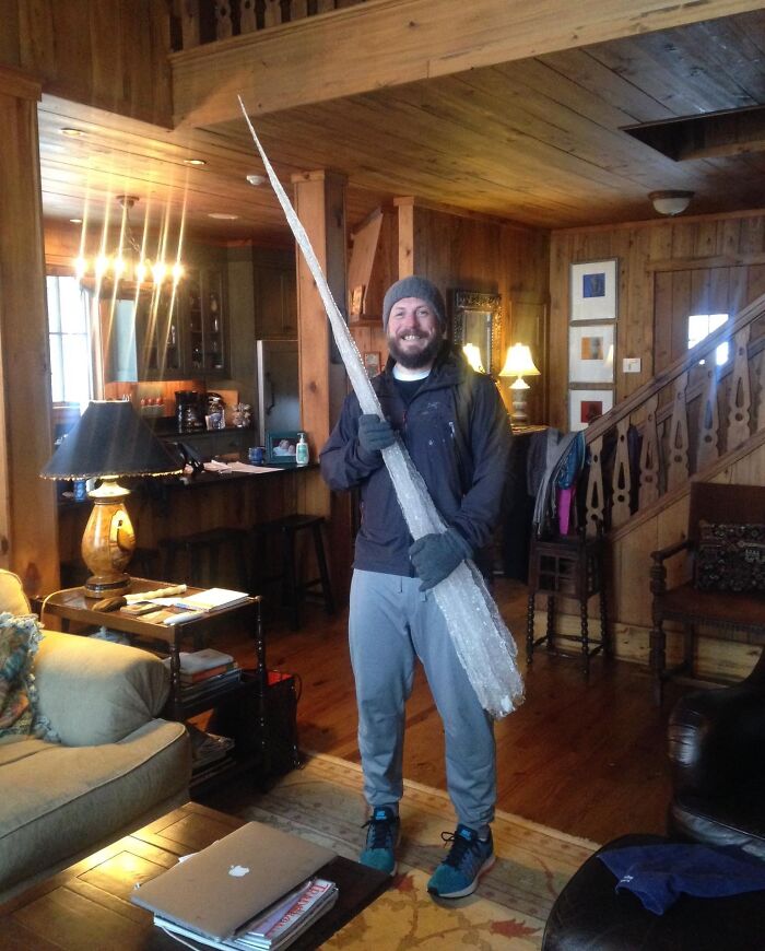 Person in a cozy cabin holding a giant icicle, creating a funny in-law family moment.