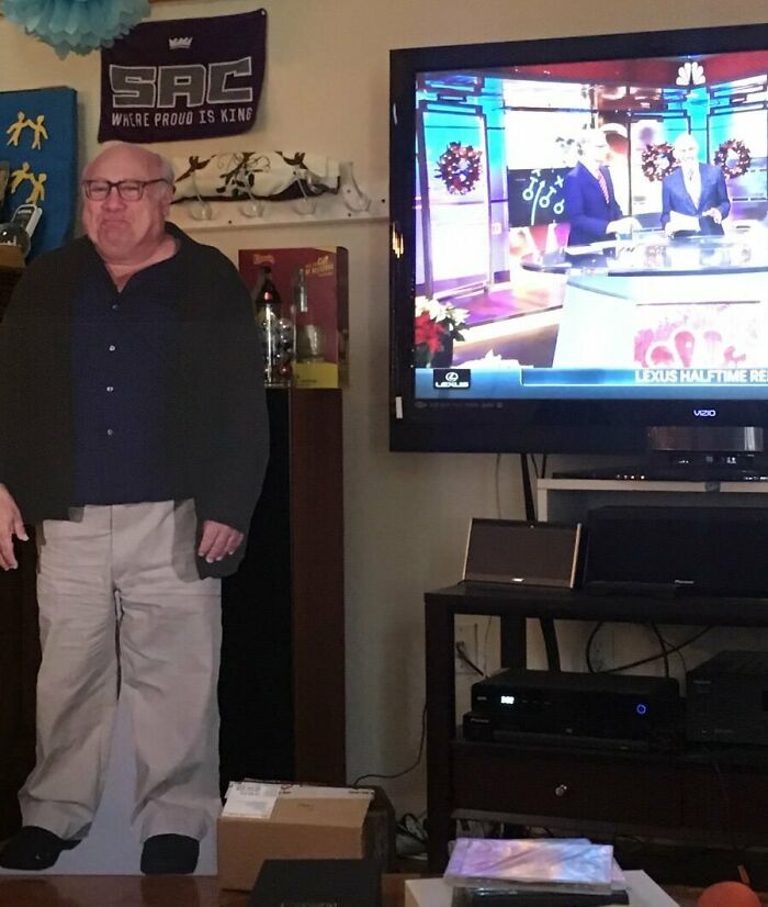 Cardboard cutout of a man humorously placed next to a TV with sports broadcast, highlighting hilarious in-laws prank.