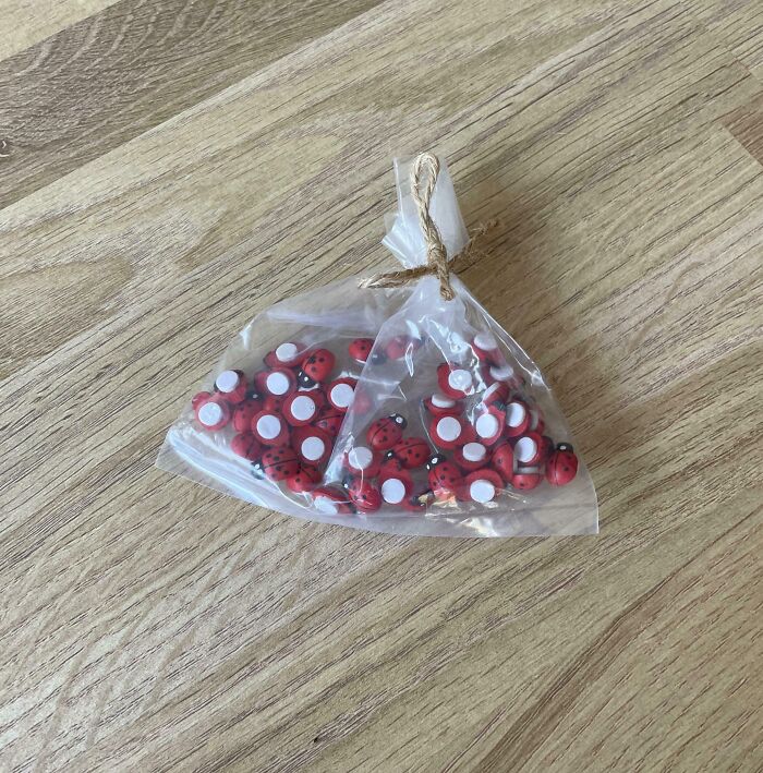 Bag of red ladybug-shaped buttons tied with twine on a wooden surface, related to Hilarious-In-Laws.