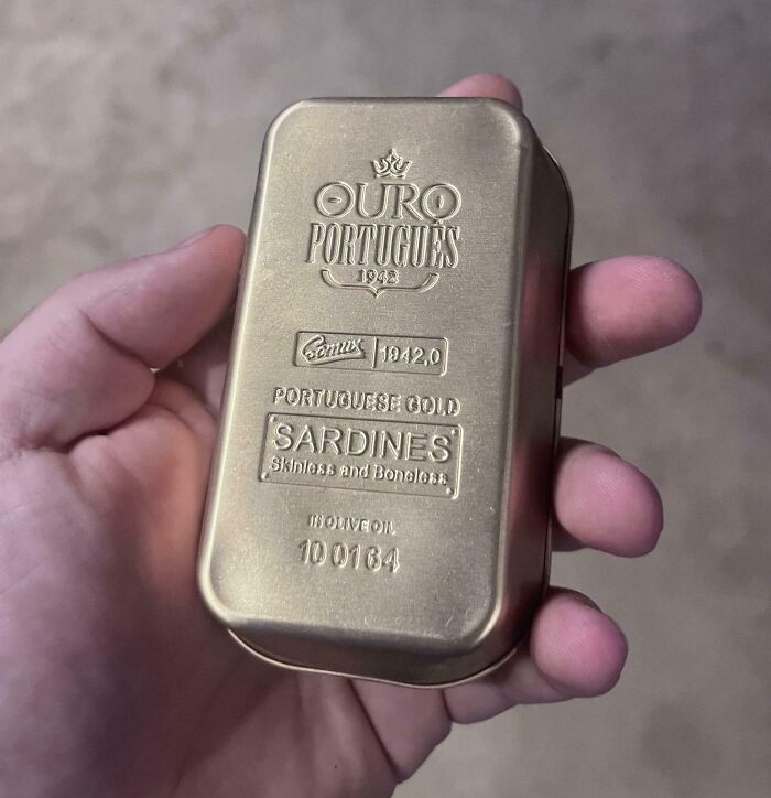 Hand holding a gold tin labeled "Portuguese Gold Sardines," resembling an unusual inheritance item.