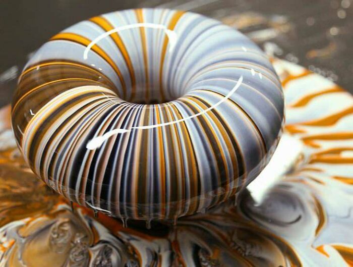 Glossy, beautifully striped donut with swirling orange and black patterns, perfect for foodies to love.