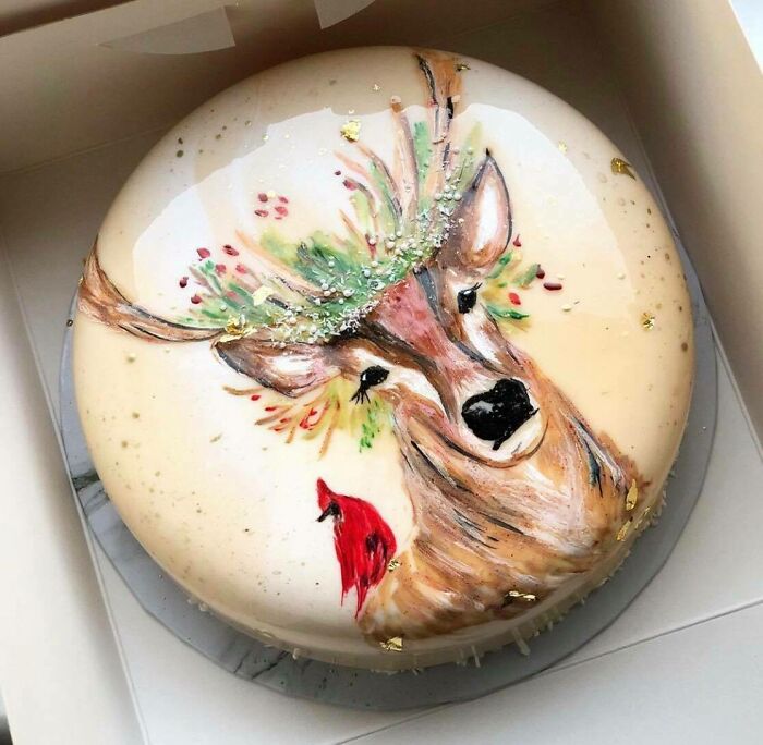 Beautifully decorated cake with a hand-painted deer and cardinal, showcasing artistic food design.