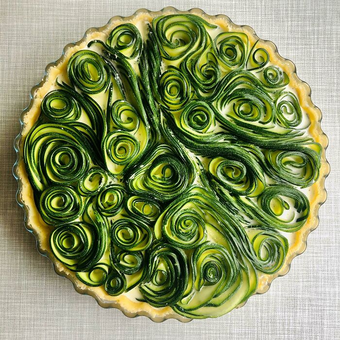 Beautiful food pic featuring a pie with spiraled zucchini design on a textured surface.