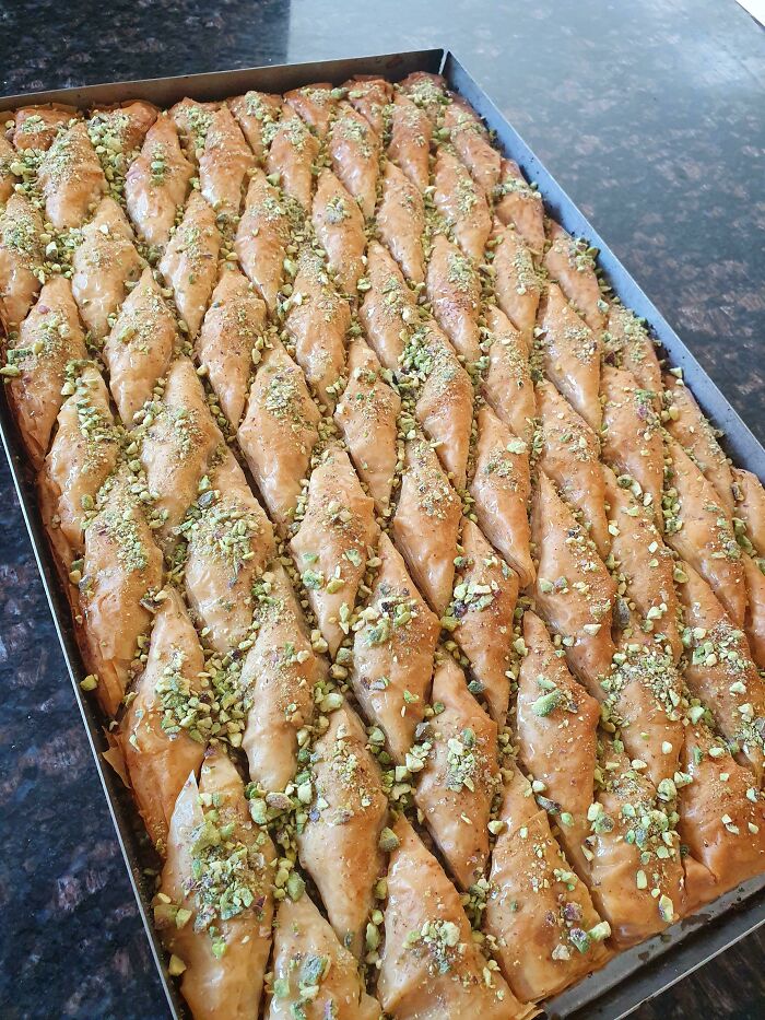 A tray of golden, flaky baklava topped with chopped pistachios, perfect for foodies to love.