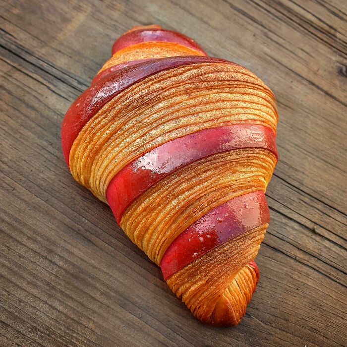 A beautifully crafted croissant with red and golden layers, perfect for foodies to love.