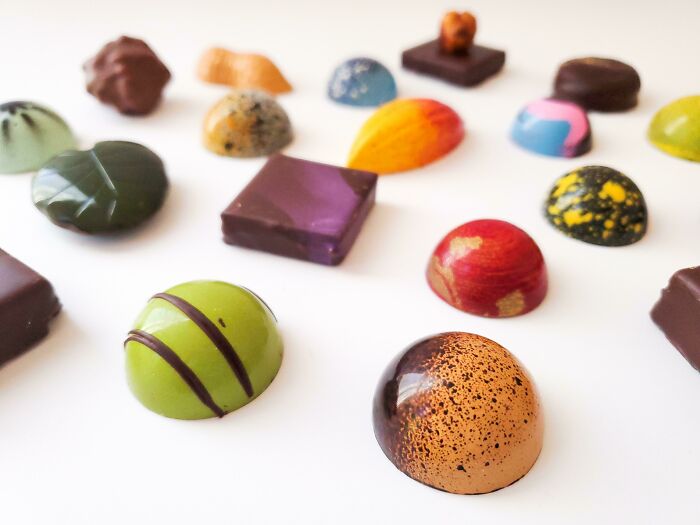 Colorful artisan chocolates displayed in rows, perfect for foodies who appreciate beautiful food creations.