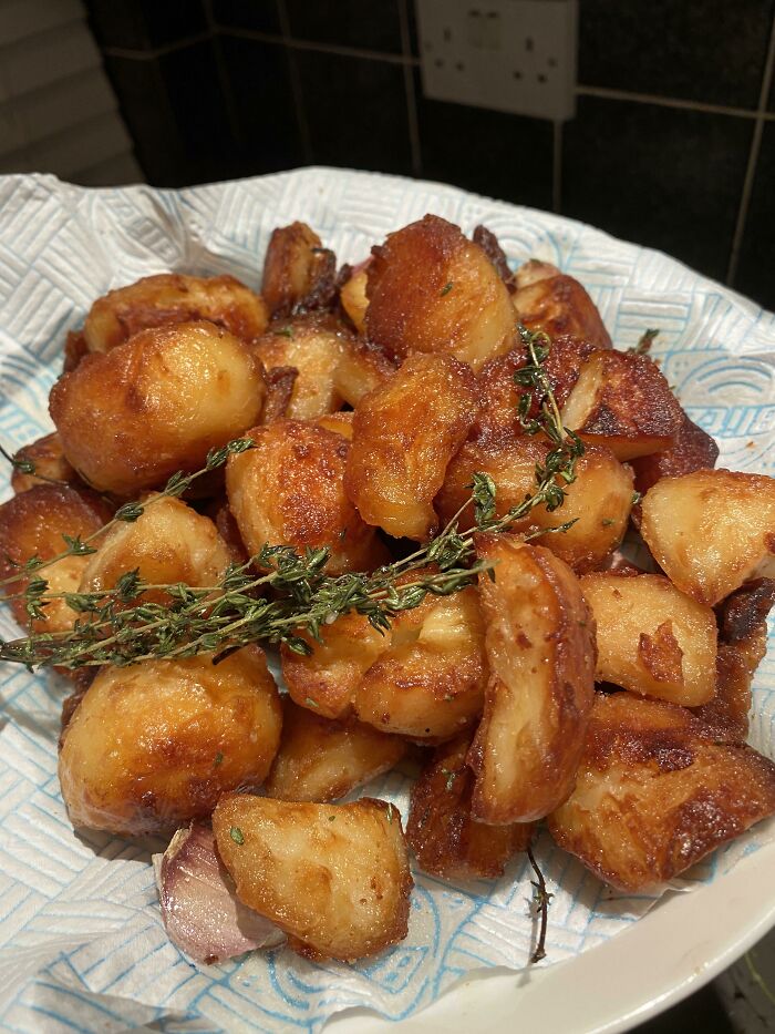 Golden crispy potatoes garnished with fresh thyme, beautifully prepared and sure to delight foodies who love delicious food pics.