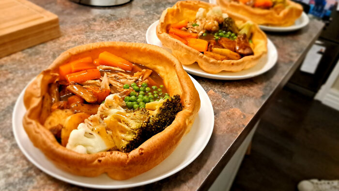 Delicious roast dinner served in a Yorkshire pudding, featuring vegetables and gravy, perfect for foodies to love.