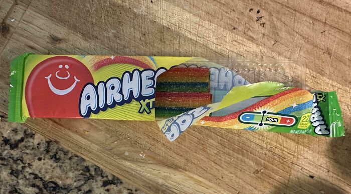 Misleading packaging design of Airheads candy, showing a partially filled wrapper on a wooden surface.