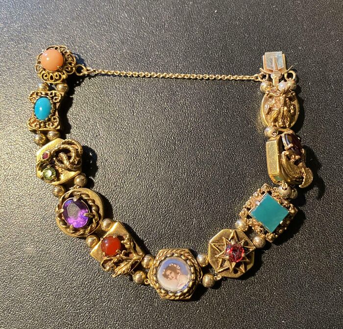 Gold charm bracelet with colorful gemstones, a unique inherited jewelry piece.