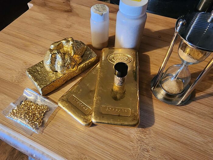 Gold bars, coins, and hourglass on wooden table showcasing a unique inheritance.