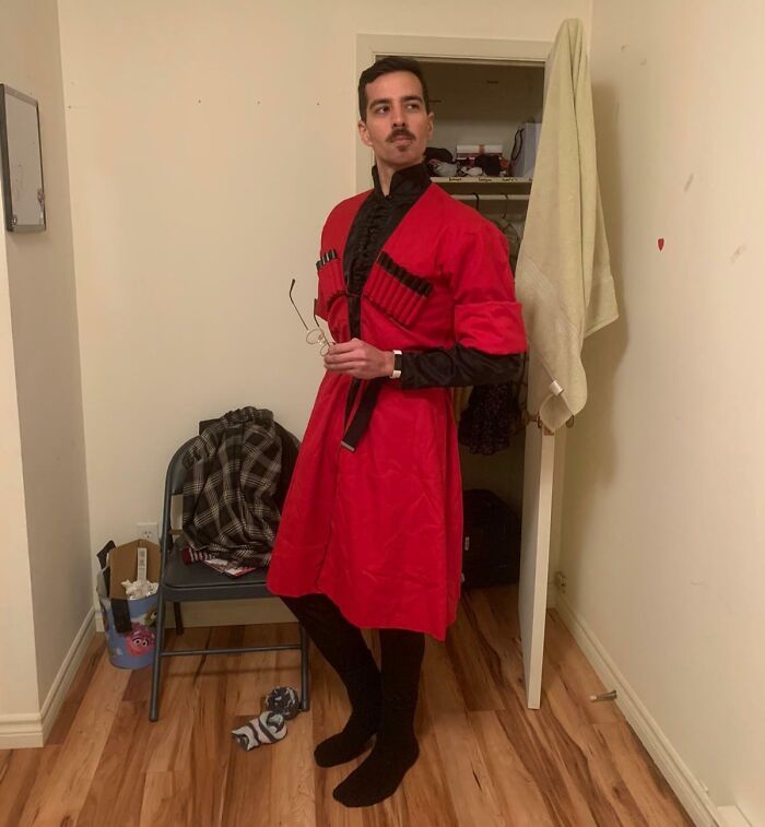 A man in a red traditional outfit stands confidently in a room, exemplifying a unique inheritance.