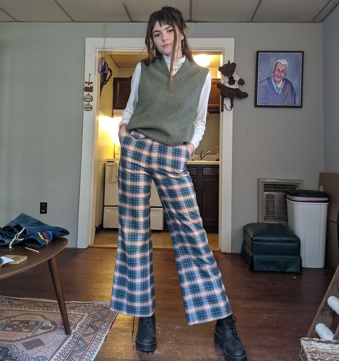 Person in stylish vintage clothing, standing in a retro-themed room with inherited decor.