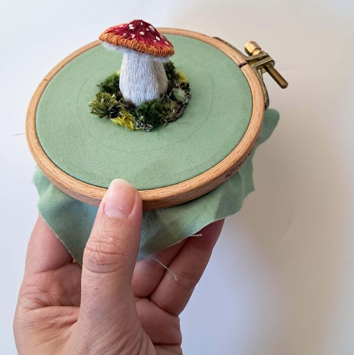 Hand holding embroidery hoop with a 3D embroidered mushroom, showcasing creative embroidery techniques.