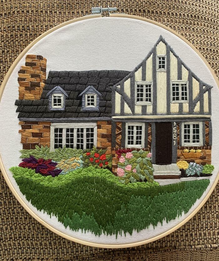 Creative embroidery of a detailed house scene in a hoop with lush garden, showcasing skillful needlework.