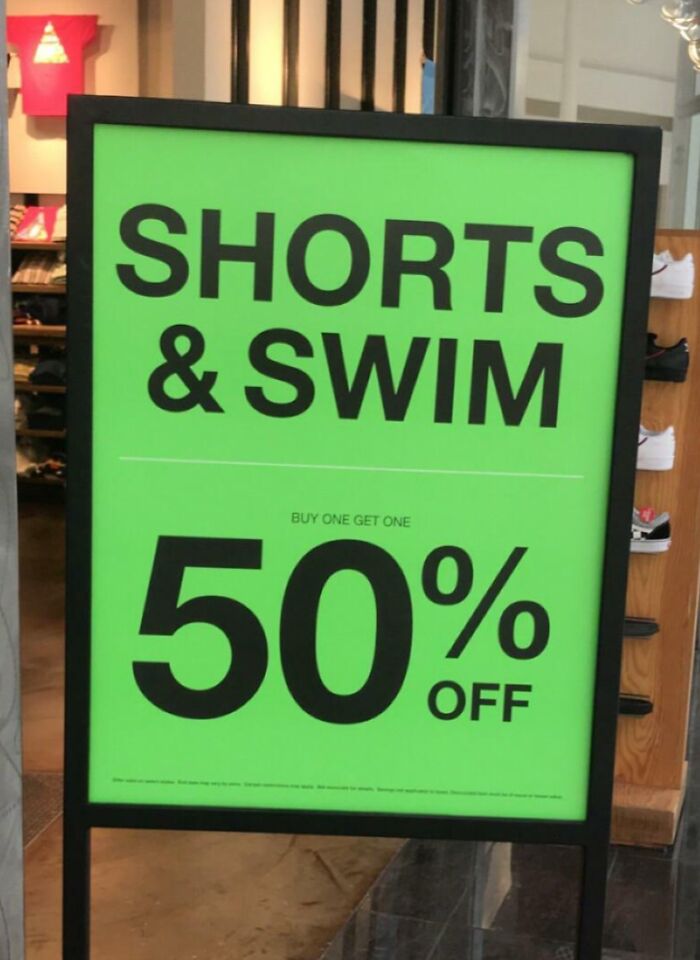 Store sign advertising "Shorts & Swim" with a deceptive marketing technique, offering 50% off.