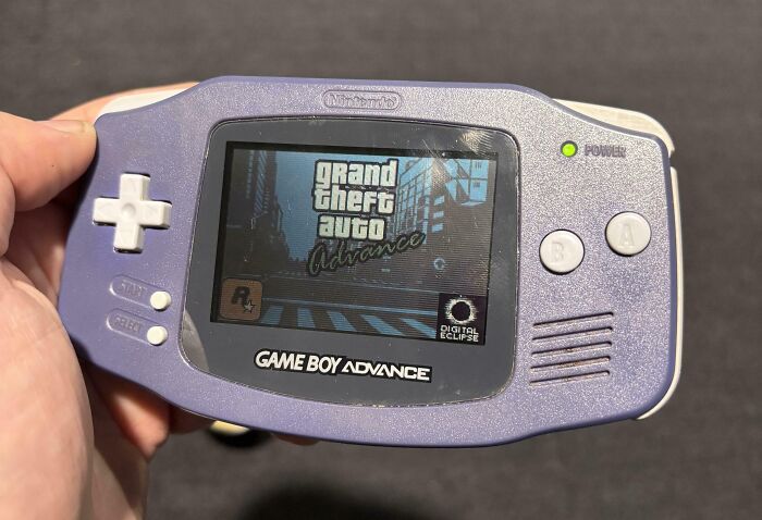 Person holding a Game Boy Advance displaying the Grand Theft Auto game screen, related to good-funny-bosses theme.