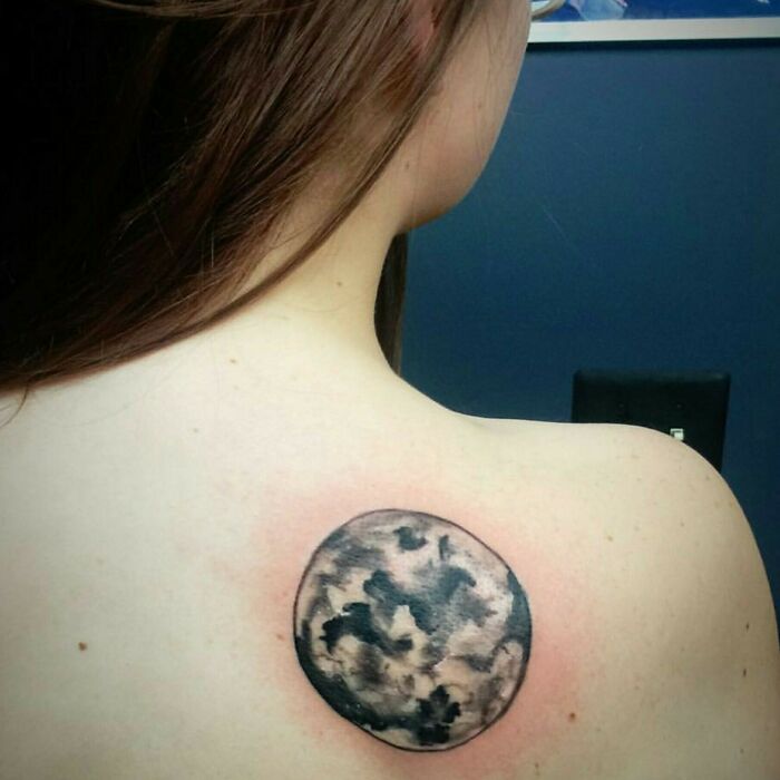 Epic tattoo fail of a poorly drawn moon on a woman's shoulder, with visible redness around the design.