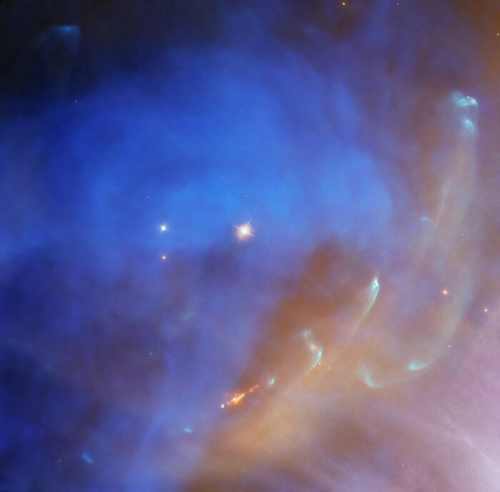 Colorful nebula with swirling blue and orange gases and starry backdrop.