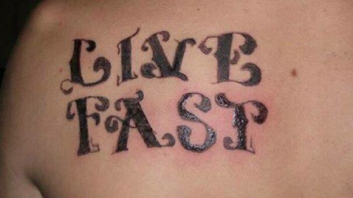 Tattoo fail with the phrase "LIVE FAST" in decorative font on a shoulder.