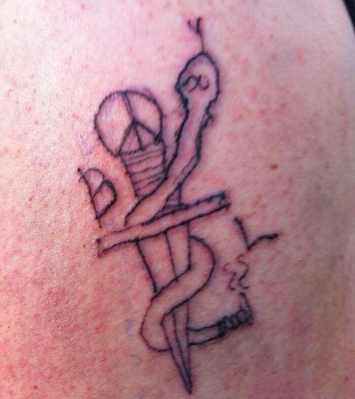 Epic tattoo fail with a roughly drawn snake wrapped around a dagger on skin.