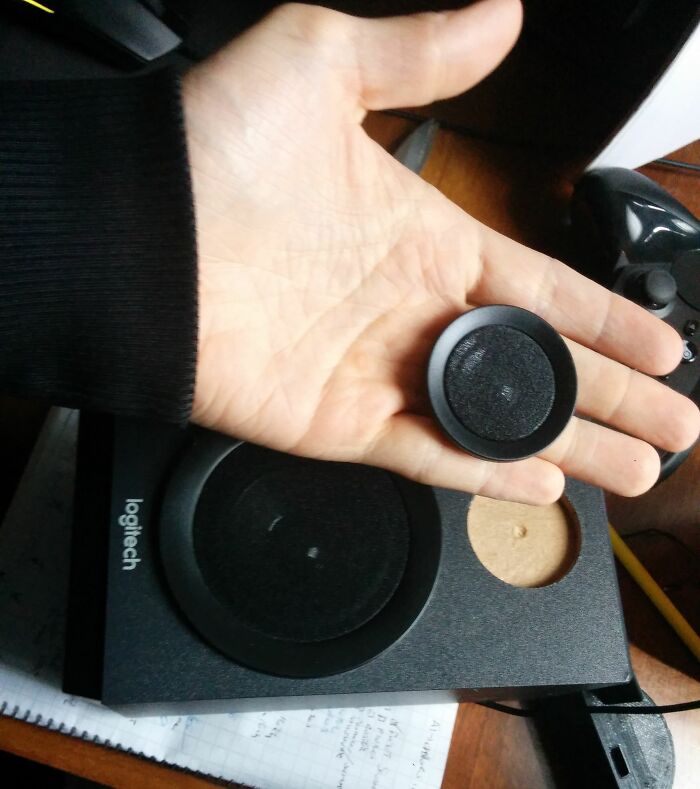 Hand holding a small speaker grille next to deceptively large packaging, illustrating misleading packaging design.