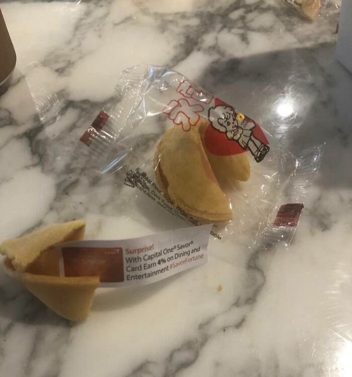 Fortune cookie with an ad inside, showcasing deceptive marketing techniques on a marble tabletop.