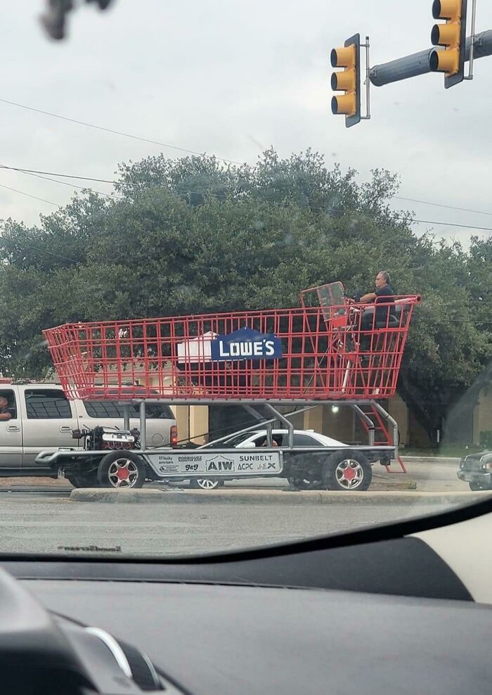 Giant shopping cart vehicle labeled "Lowe's" seen on the road, capturing attention with its unusual design.