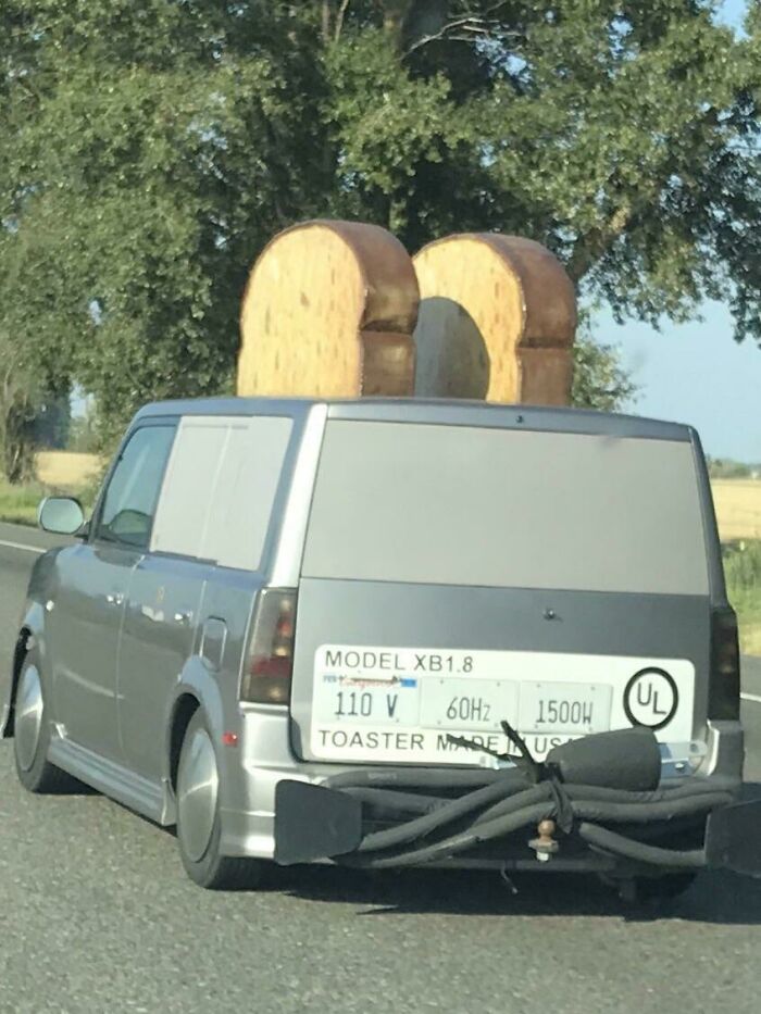 A van on the road with giant toast on its roof, resembling a toaster.