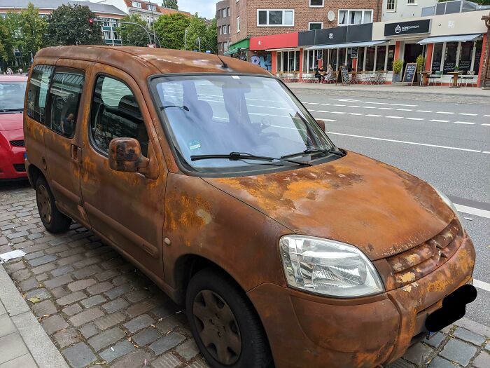 Rusted car parked on a city street, exemplifying car-fails with its deteriorated exterior.