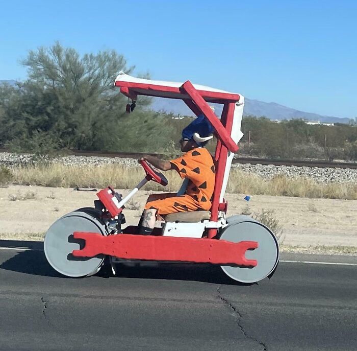 Person in a Flintstones-themed vehicle driving on a road, showcasing interesting things on the road.