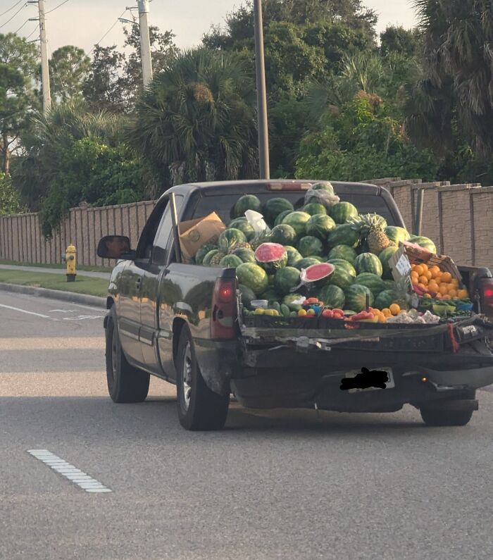 Pickup truck loaded with various fruits including watermelons on the road.