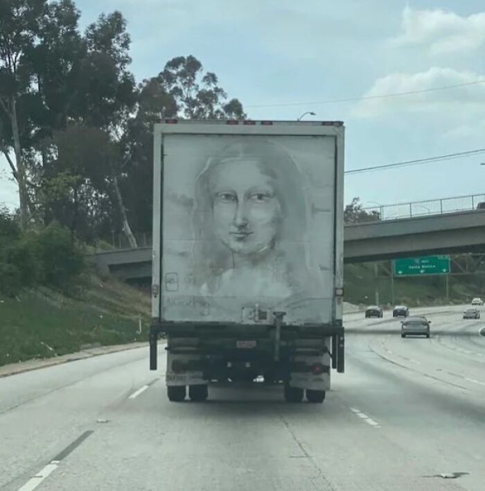 Truck with Mona Lisa painting on the road, capturing an interesting sight.