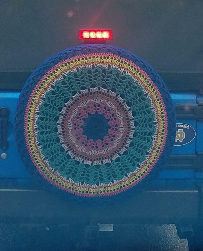 Crocheted tire cover with colorful patterns spotted on the road.