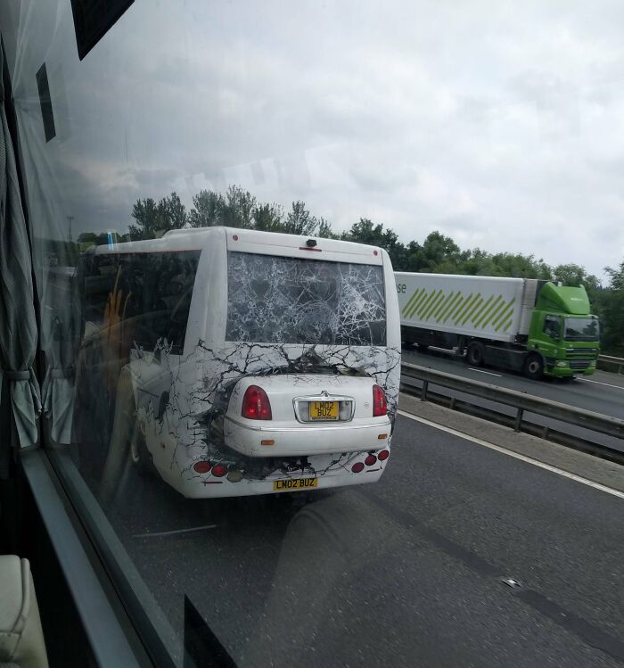 Bus with a humorous design on the highway, simulating a cracked window with a car's rear.