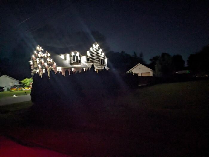 Dimly lit house adorned with excessive outdoor lights, illustrating money can't buy taste.