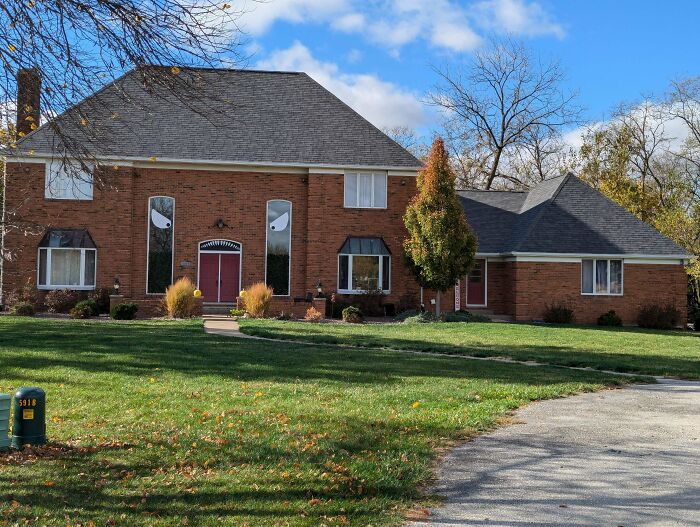 Large red brick house with mismatched architectural elements, illustrating that money can't buy taste.