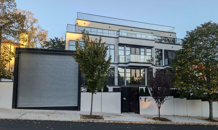 Modern house with large glass windows, surrounded by trees, demonstrating that money can't buy taste.