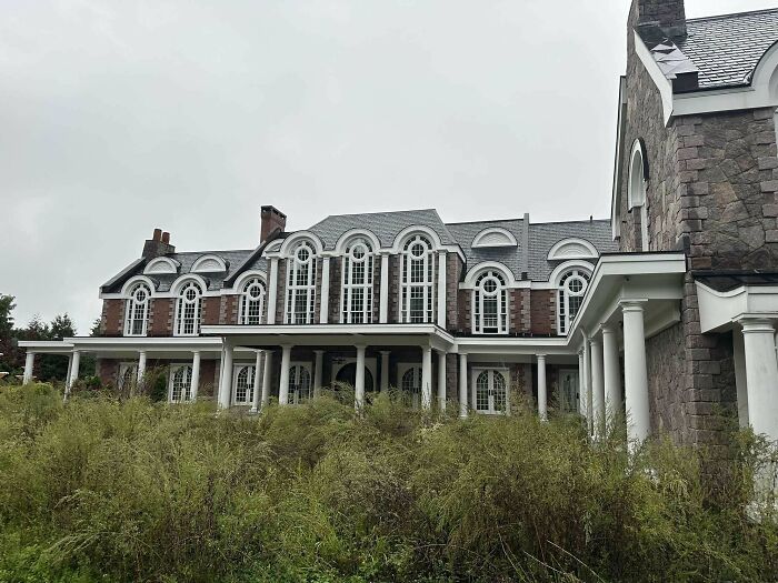 Mansion with grand arches and overgrown garden, illustrating that money can't buy taste.