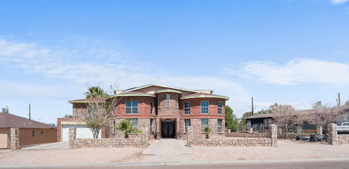 Unusual brick house design with stone wall, showcasing how money can't buy taste.