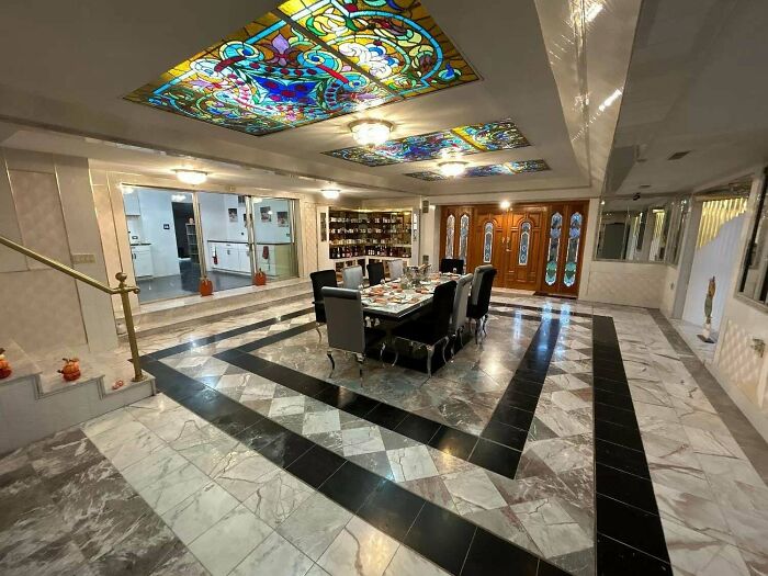 Luxurious dining room with ornate stained glass ceiling, showcasing how money can't buy taste.