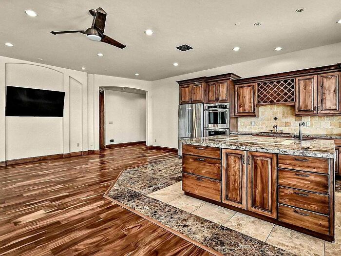 Luxury kitchen with wooden cabinets and marble floor, proving money can’t buy taste.