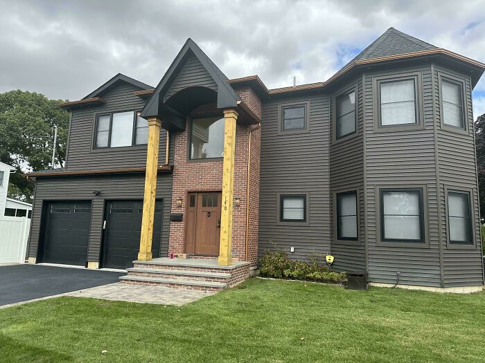 Unusual house design with mismatched columns and dark siding, illustrating that money can’t buy taste.