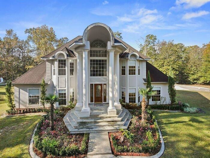 Luxurious house with large columns and intricate landscaping, illustrating that money can't buy you taste.