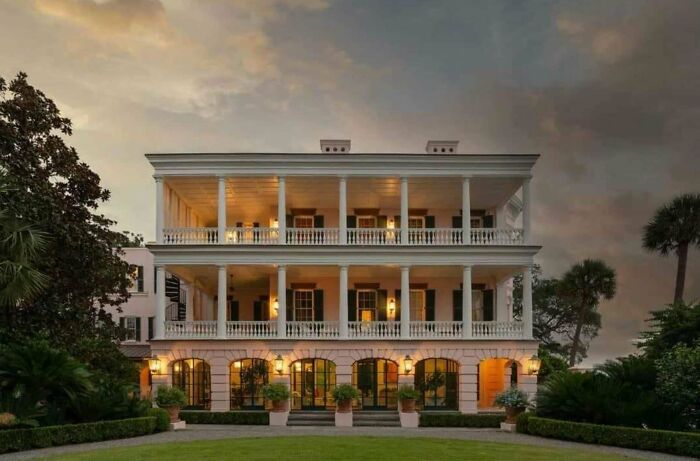 Luxurious three-story mansion with multiple balconies, showcasing elegant architectural design at dusk.