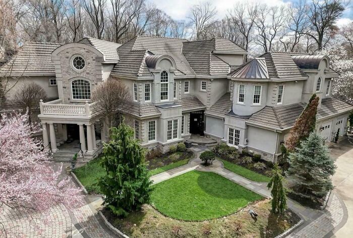 Luxury house with elaborate design, showcasing that money can't buy taste, surrounded by greenery and trees.