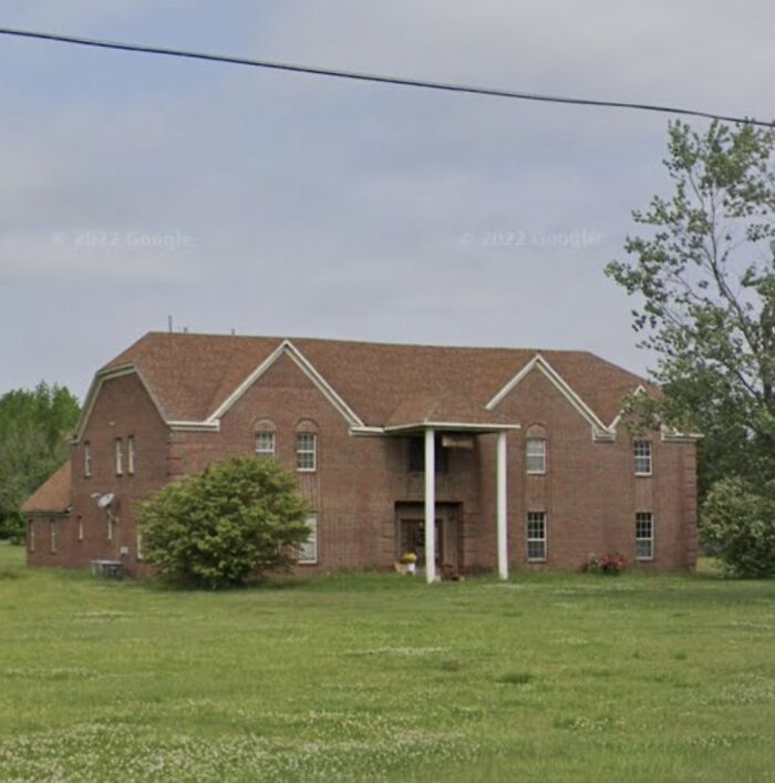 Large brick house with tall columns in a rural setting, exemplifying that money can't buy taste.