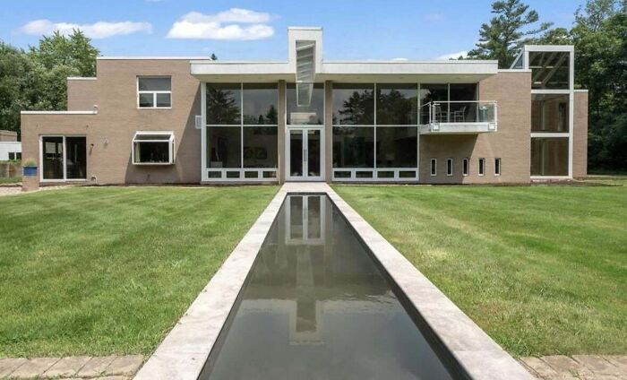 Modern house with unusual design features, showcasing that money can't buy taste. Reflective pool in front yard.